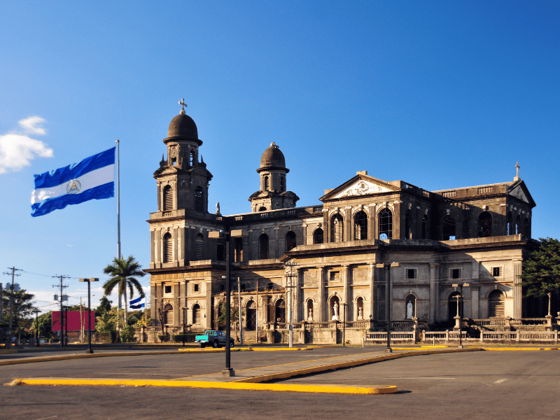 Die Alte Kathedrale von Managua, umgeben von einer weiten Plaza und der wehenden Flagge Nicaraguas, ist ein historisches Wahrzeichen der Hauptstadt und eine Sehenswürdigkeit.