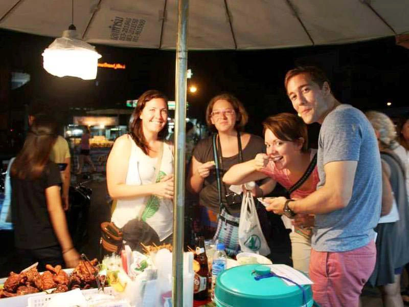 Touristen kaufen Essen an einer Garküche in Thailand