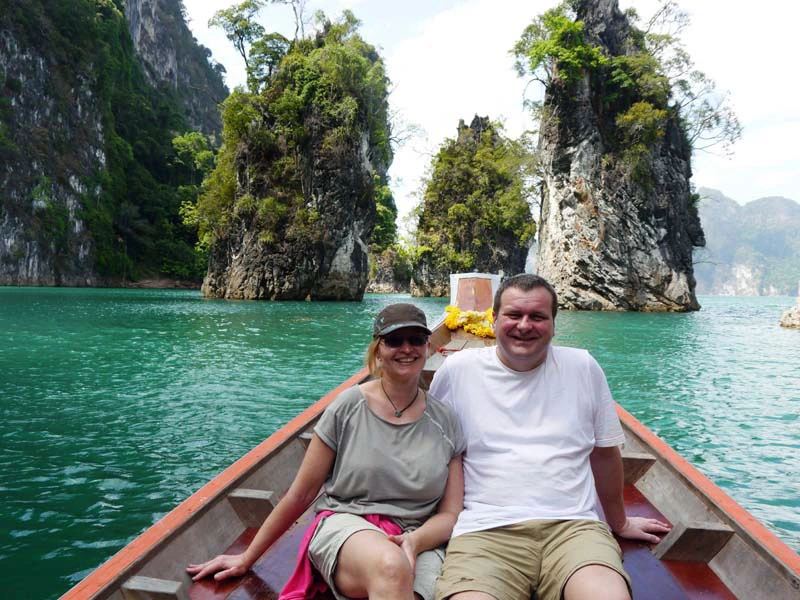 Reisende im Longtailboot in einer Bucht in Thailand