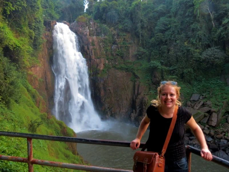 Junge Frau am Geländer zentral vor einen kleinen Wasserfall