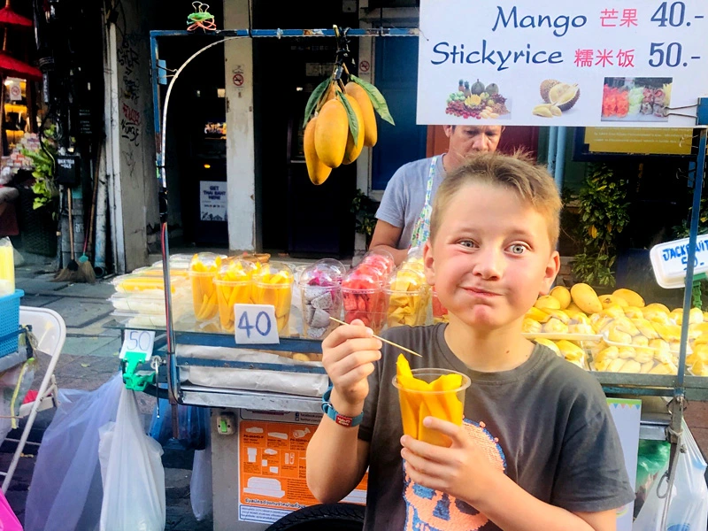 Kind mit Mango in Bangkok