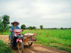 Einheimische auf einem Roller mit Seitenwagen au einem Feldweg in Thailand