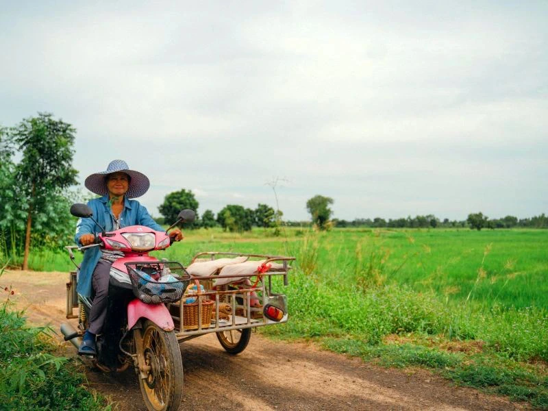 Einheimische auf einem Roller mit Seitenwagen au einem Feldweg in Thailand