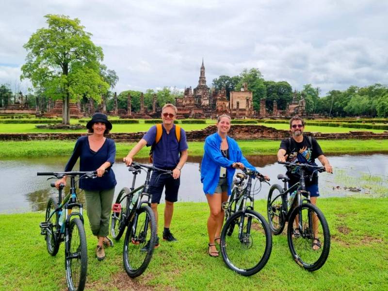 Touristen mit dem Fahrrad in der Tempelanlage in Sukhothai, Thailand