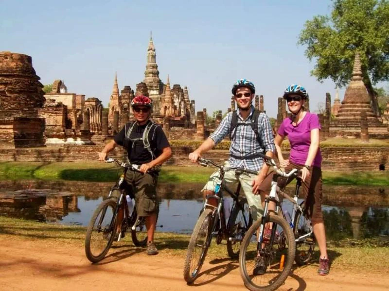 Touristen mit dem Fahrrad in der Tempelanlage in Sukhothai, Thailand