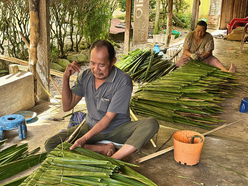 Einheimischer Mann bei der Herstellung eines Plamdachs in Bukit Lawang, Indonesien