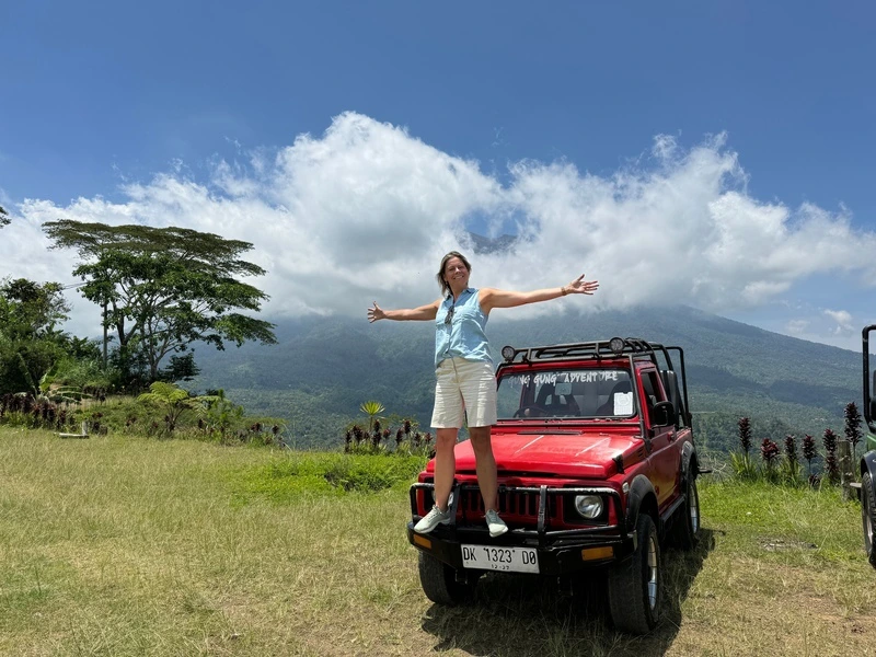 Frau posiert auf Jeep vor weiter Landschaft auf Bali