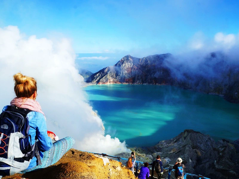 Reisende am Rande des Kratersees im Ijen Vulkan auf Java