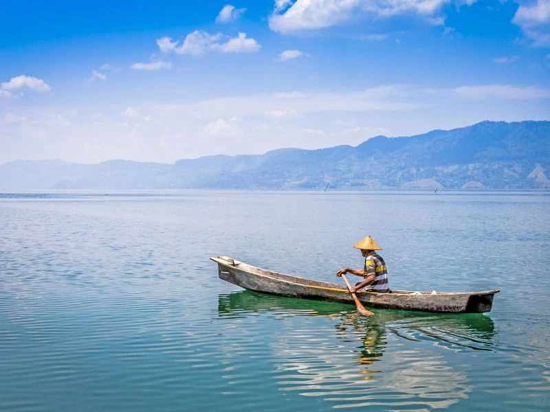 Mann auf einem Boot auf dem Tobasee in Samosir auf Sumatra in Indonesien