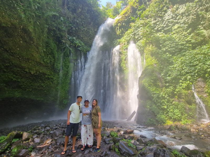 Touristen mit lokaler Reiseleiterin vor einem Wasserfall bei Senaru auf Lombok