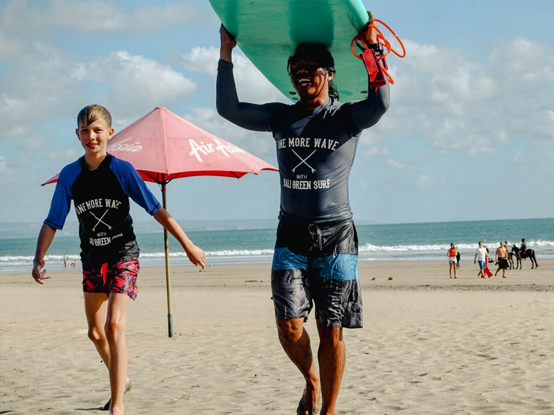 Kind mit Surflehrer am Strand