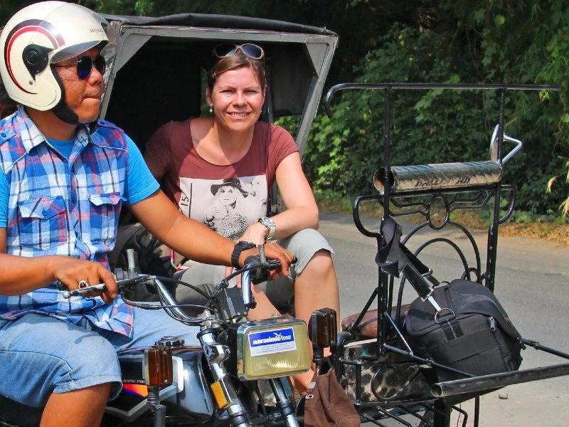 Frau als Beifahrerin in einem Becak mit lokalem Fahrer in Indonesien