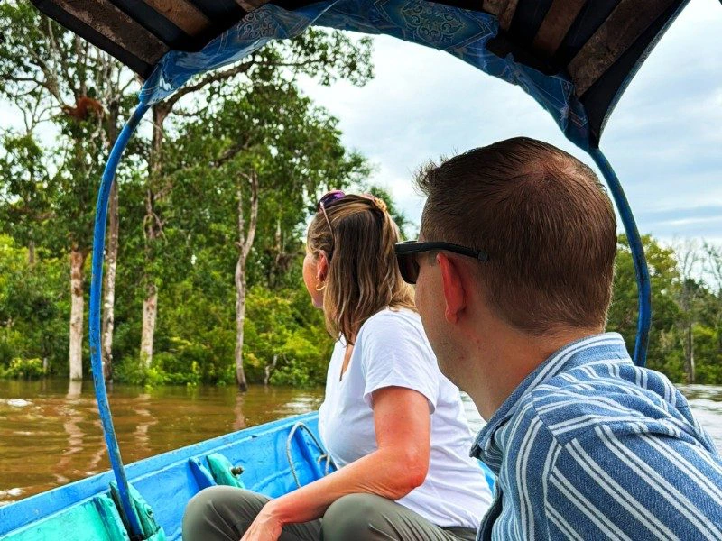 Touristen fahren auf Boot an einer bewaldeten Insel auf Kalimantan vorbei