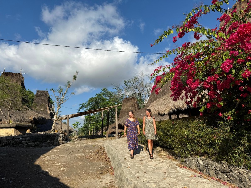 Zwei Touristinnen spazieren durch ein Dorf auf Sumba, Indonesien