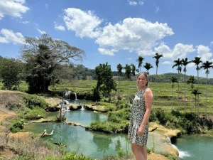 Touristin vor einem Wasserfall im Reisfeld auf Sumba, Indonesien