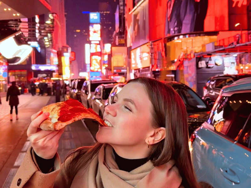 Frau isst Pizza am Times Square in New York in den USA