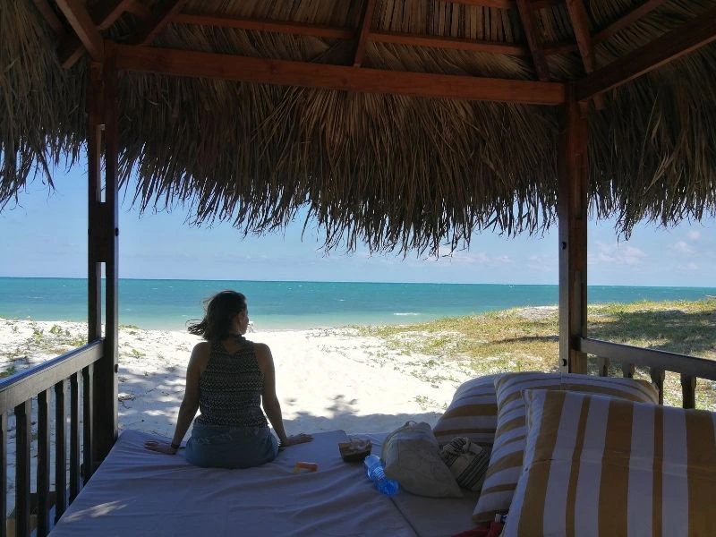 Frau sitzt am Strand Cayo Levisa mit dem Meer im Hintergrund