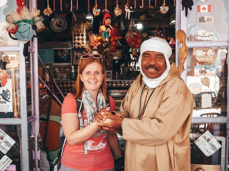 Reisende mit Händler vor seinem Shop in Marrakesch