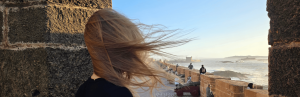 Frau mit wehenden Haaren mit Blick auf Kanonen auf der Burgmauer und das Meer