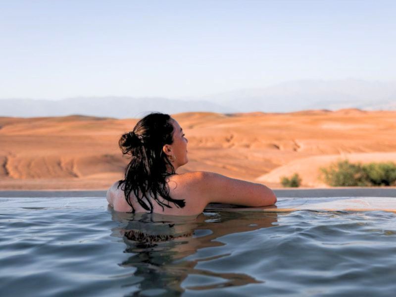 Reisende im Pool mit Blick auf die Wüste von Agafgay in Marokko