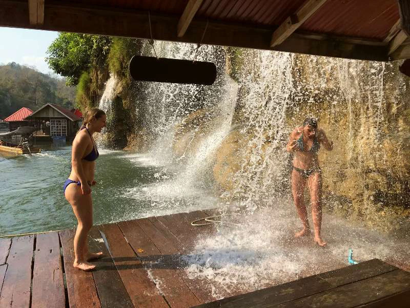 Touristen erfrischen sich unter einem Wasserfall im Sai Yok Nationalpark in Thailand