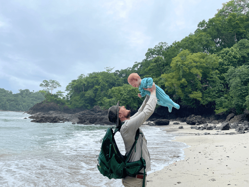 Vater hält Sohn am Strand hoch in der Luft