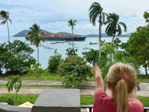 Mädhcen schaut einem Schiff bei der Durchfahrt im Panamakanal zu