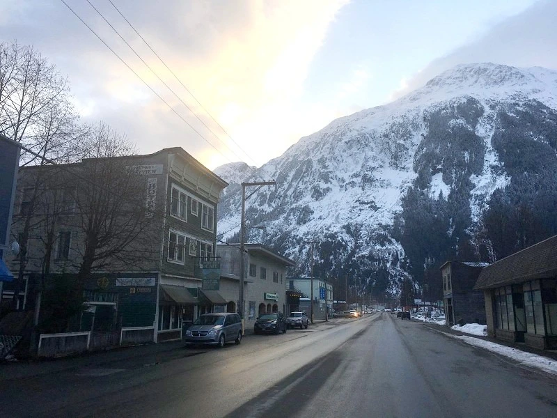 Straße mit Häusern auf beiden Seiten, die zu einem schneebedeckten