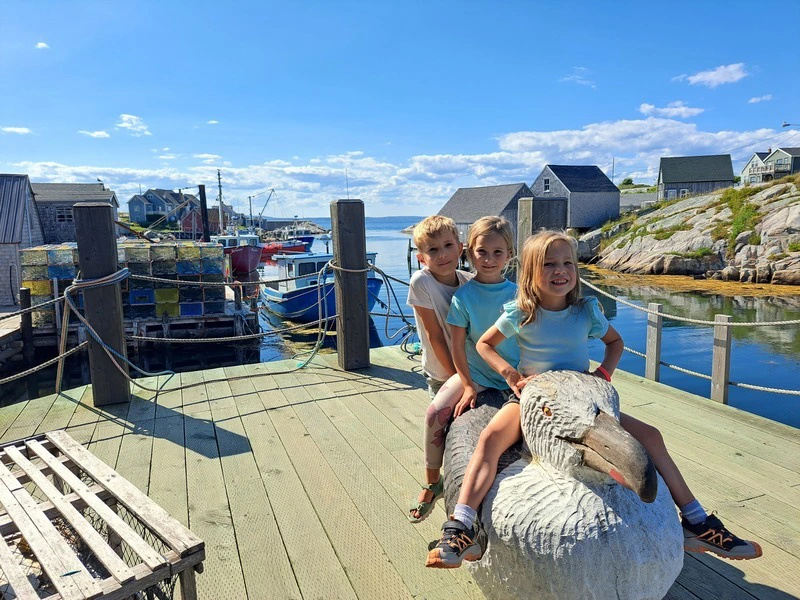 Kinder auf einer Seehund Statue in Peggys Cove