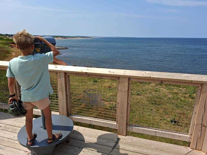 Kind schaut durch ein Fernrohr auf den Atlantik in Kanada