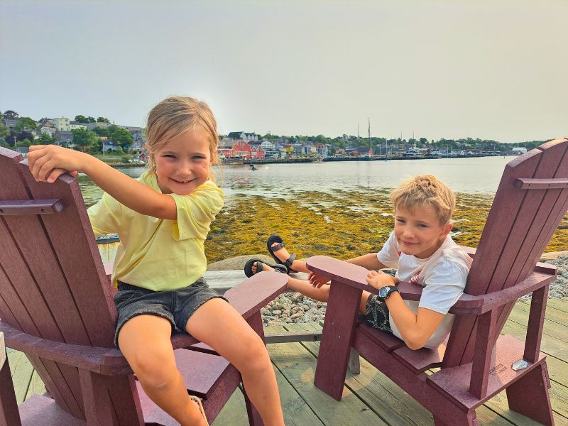 Kinder auf Stühlen, im Hintergrund das Meer