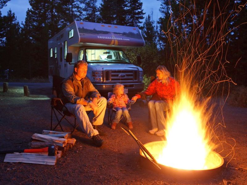 Familie vor einem Lagerfeuer auf dem Campingplatz in Kanada