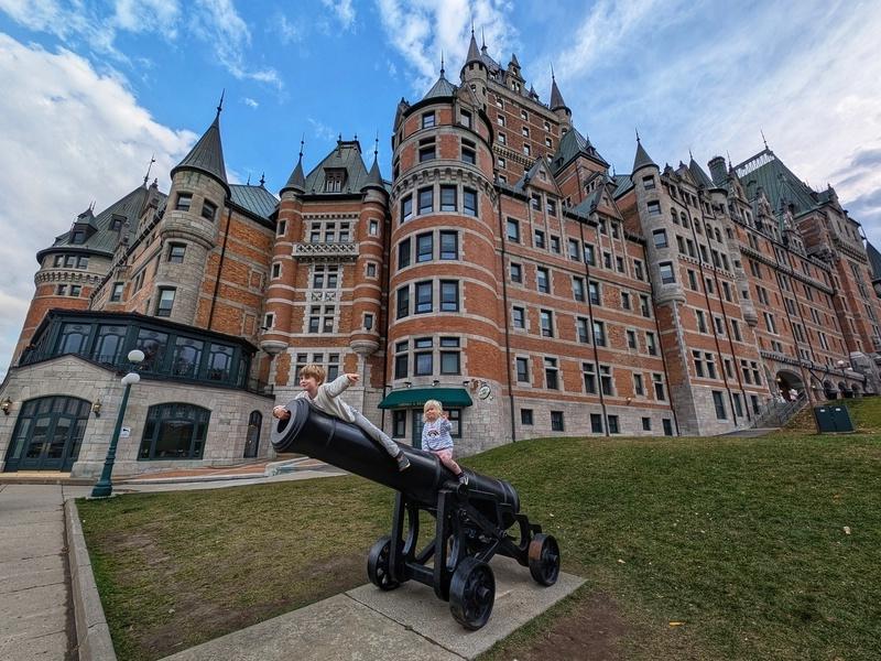 Kinder auf einer alten Kanone vor einem Schloss in Quebec, Kanada