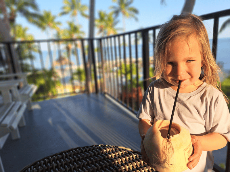 Kind trinkt aus einer Kokosnuss