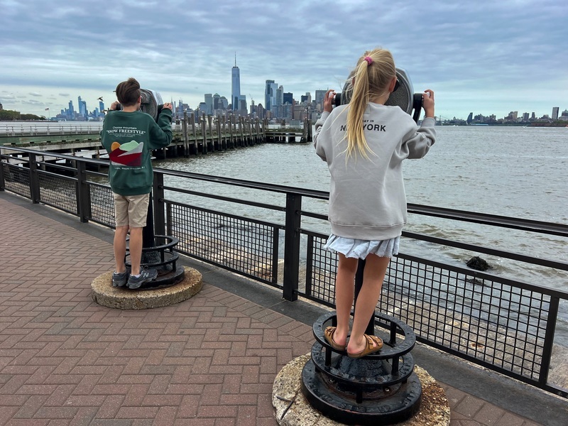 Kinder, die mit einem Fernglas auf die New Yorker Skyline schauen