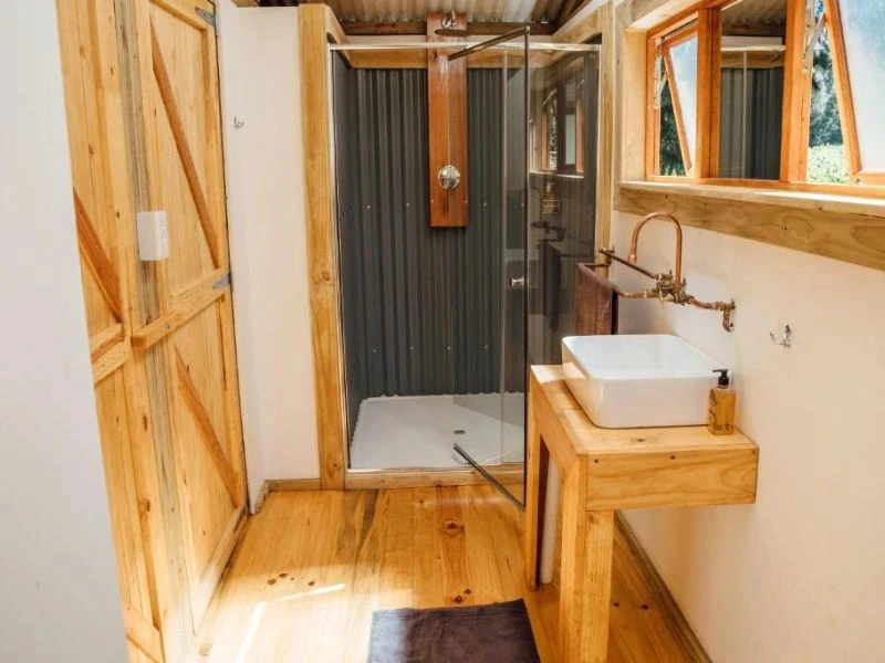 Hölzernes Badezimmer mit modernem Waschbecker und Dusche in Magoebaskloof