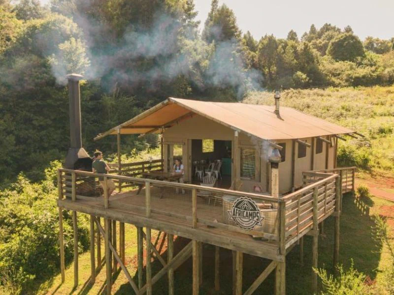 gemütliche Holzhütte auf Stelzen mit überdachter Terrasse Möbeln und Whirlpool in den grünen Hügeln der Magoebaskloof