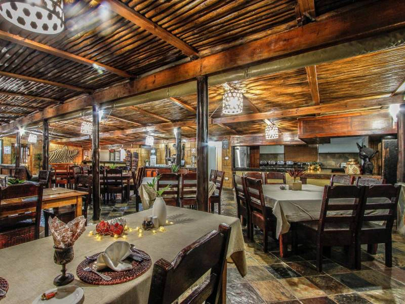 Gemütlicher Innenraum eines Restaurants im hölzernen Ambiente bei gedämpften Licht im Hluhluwe Wildpark