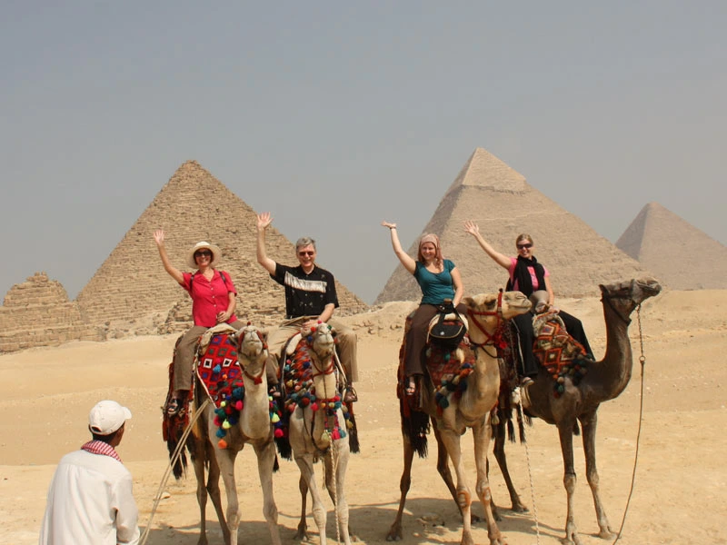 VIer Kamele mit Menschen vor den Pyramiden in Kairo, Ägypten