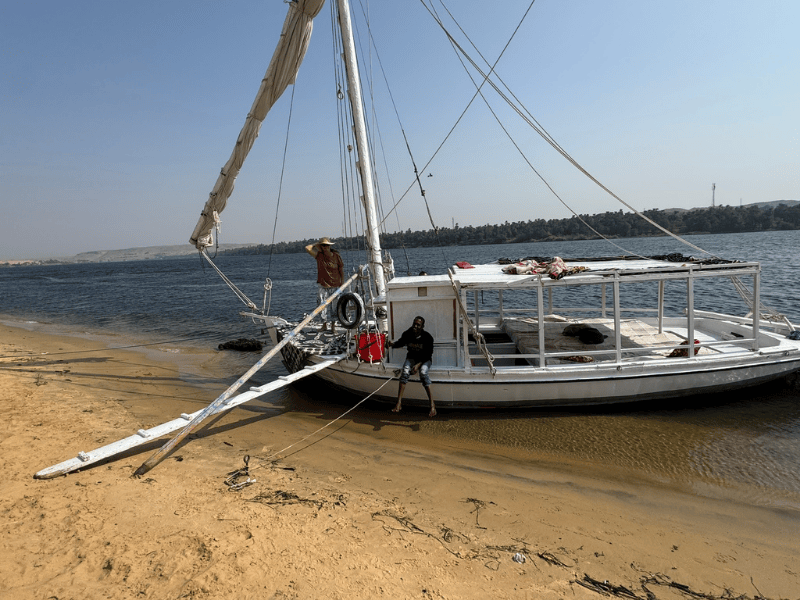 Feluke mit Crewmitglied am sandigen Ufer des Nils