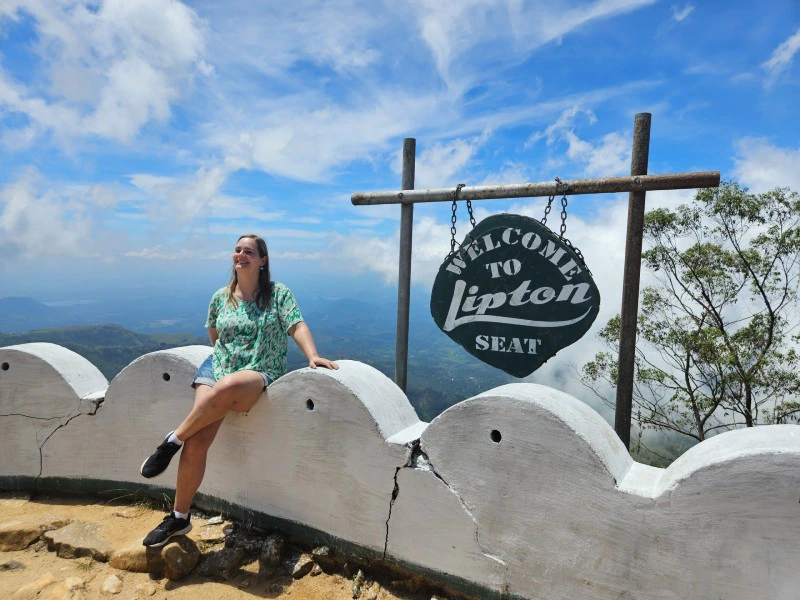 Frau vor dem Schild des Lipton Seat in Sri Lanka
