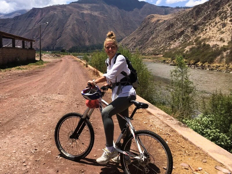 Frau, die mit ihrem Fahrrad im Heiligen Tal in Urubamba, Peru