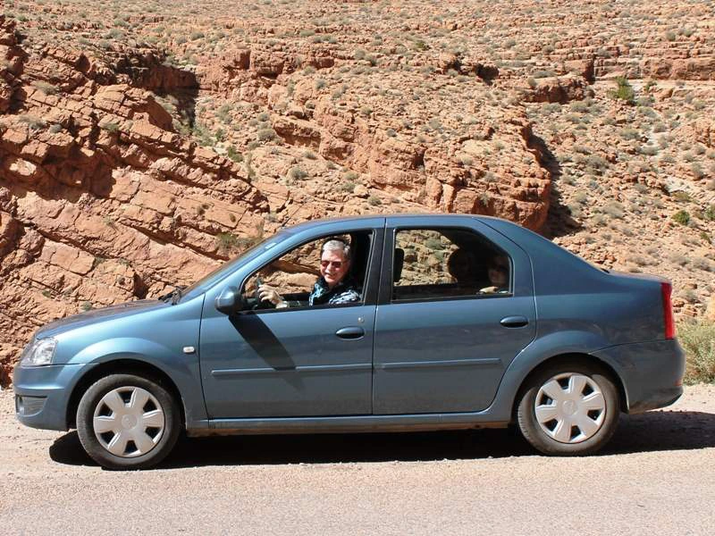 Mittelgroßer Mietwagen vor einem roten Felshügel