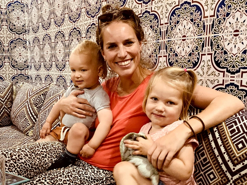 Mutter mit zwei Kindern im Arm auf einer Couch im Homestay in Marokko