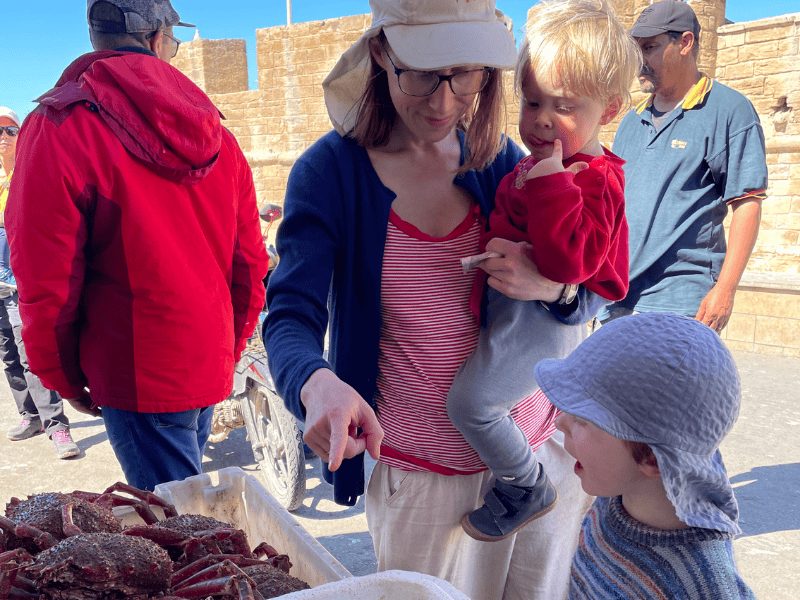 Mutter erklärt Kindern welche Meeresfrüchte es auf dem Markt in Essaouira zu kaufen gibt