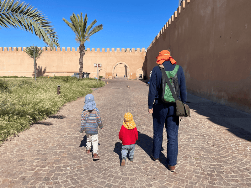 Rückenansicht von Vater und Kleinkindern, die auf Stadtmauer in Essaouira zulaufen