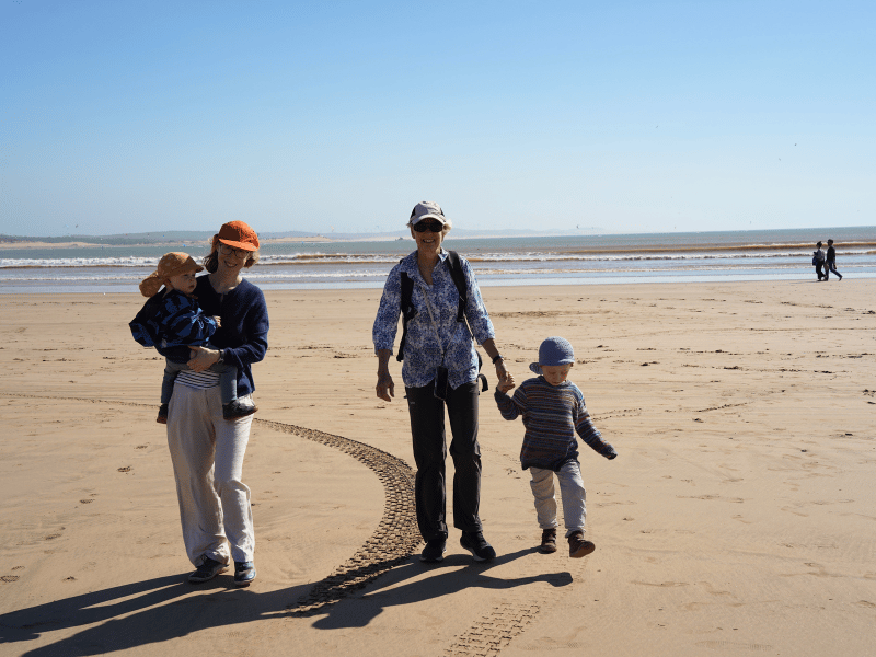 Zwei Frauen mit zwei Kleinkindern laufen am Strand weg vom Meer in Essaouira