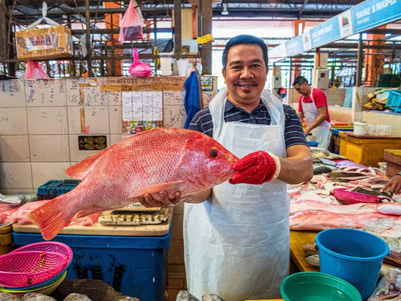 Einheimischer mit einem Fisch auf einem Markt in Kuching, Borneo