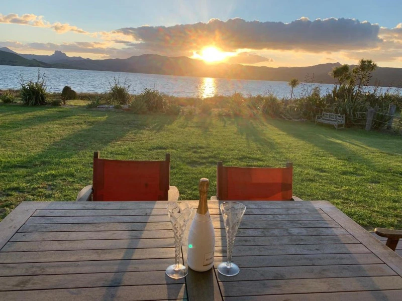 Sonnenuntergang bei einem Glas Sekt in der Unterkunft, Coromandel, Neuseeland.