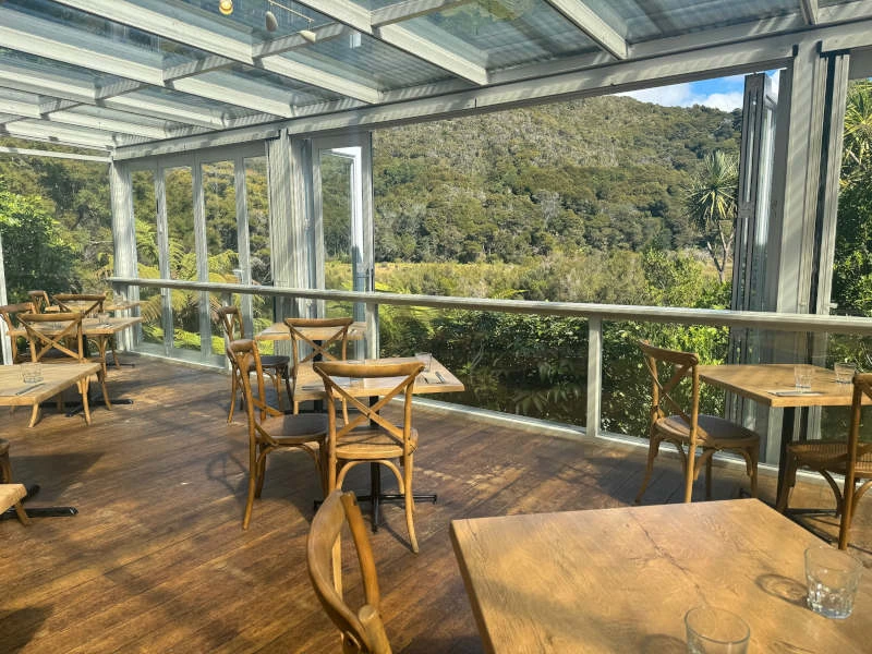 Terrasse mit Tischen und Stühlen und toller Aussicht in der Lodge Unterkunft im Abel Tasman Nationalpark in Neuseeland